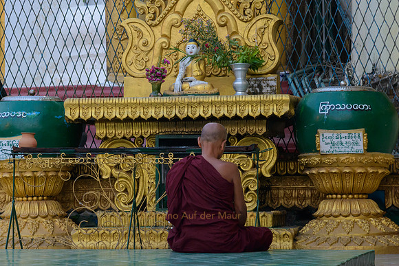 Mönch meditiert vor Buddhastatue