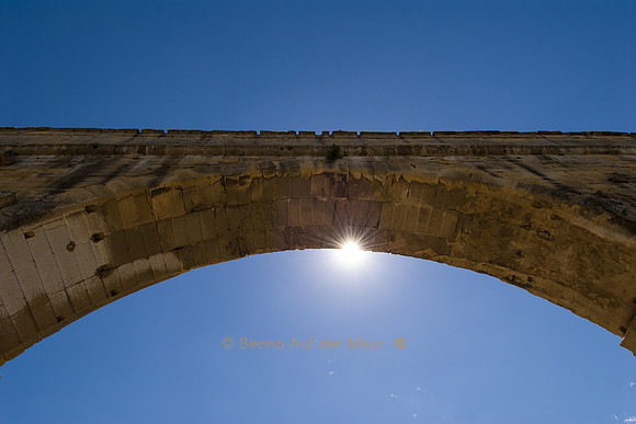 Sonne scheint unter dem Bogen des Pont du Gard durch