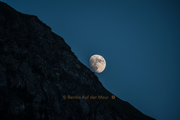 Der Mond taucht hinter einem Felshang auf