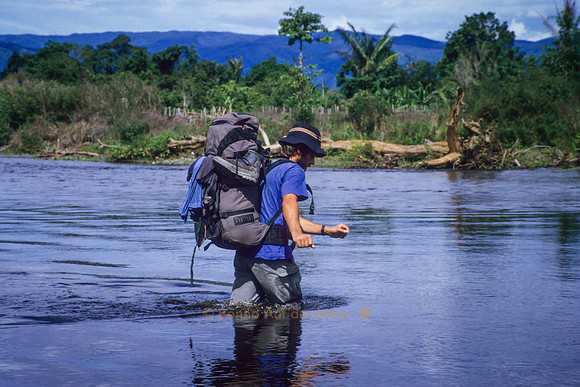 Trekker durchquert einen Fluss; auf dem Weg von Tuare nach Gintu – Nord-Sulawesi