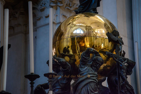 Mehrere Figuren stemmen eine grosse, goldene Kugel